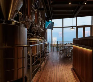 Industrial-style brewery interior featuring large metal tanks and a wooden floor.