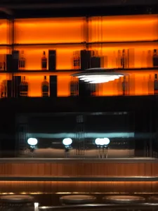 A modern bar interior featuring glass walls and warm lighting.