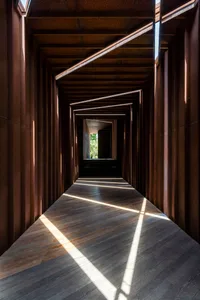 A dark, wooden and concrete corridor featuring geometric lighting patterns.