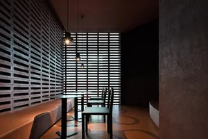 Modern industrial restaurant interior with concrete walls and wood seating.