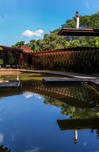 A minimalist pavilion featuring a wooden structure and a tranquil water body in a garden setting.
