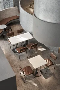 A modern cafe interior featuring concrete furniture and flooring.