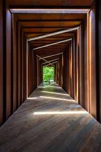 A modern corridor with a wooden floor and walls extending into the distance.