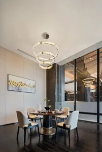 Modern dining room featuring a glass-topped dining table surrounded by cushioned chairs, under a contemporary crystal chandel
