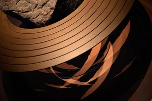 A piece of abstract metallic mixed-media artwork with circular and geometric shapes.