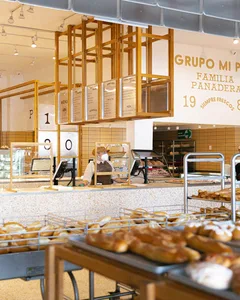 麵包店室內空間，木製櫃檯展示烘焙商品，員工戴著口罩。