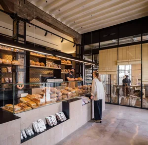 A modern retail shop with industrial design elements, featuring exposed concrete walls, wooden shelves, and glass display cas
