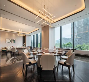 A modern minimalist dining room featuring luxury materials with a large round table and white chairs.