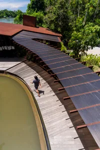 Modern architecture featuring a floating metal roof supported by wood beams and glass panels.