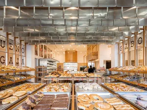 A modern bakery with metal walls and ceramic countertops filled with various baked goods.
