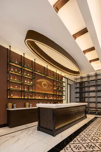 Modern bar interior with marble countertop and metal accents, illuminated by circular lighting fixture.