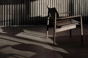 Modern chair with wooden staine in a dark, minimalist interior setting.