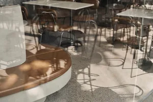 A modern coffee shop with concrete flooring and furniture.
