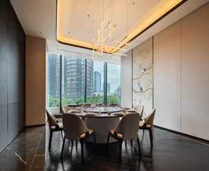 Modern dining room with a concrete floor, round table, and chairs, featuring a minimalist design with a contemporary chandeli