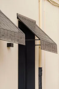 Metal grid window with concrete awning in a modern residential entryway design