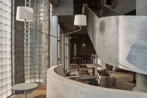 Interior of a modern industrial coffee shop featuring concrete and glass materials.