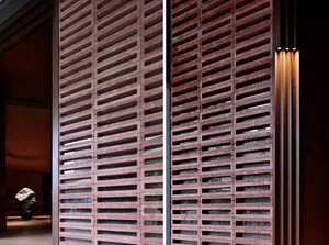 A close-up view of a contemporary interior featuring a brick barrier with horizontal slats and a warm, ambient lighting setup