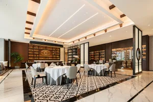 A spacious contemporary restaurant interior with marble floor tiles and elegant white dining tables.