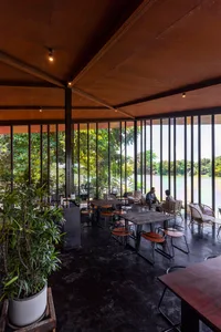 Modern restaurant interior with metal tables, glass walls, and black flooring