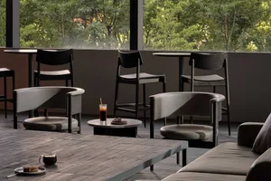 A minimalist cafe interior with wood and leather furniture, tables, and chairs.