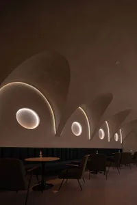 Modern minimalist restaurant interior with circular cutouts in the concrete ceiling.