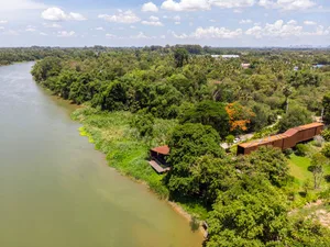 Aerial view of a riverbank, with lush greenery and a modern structure.