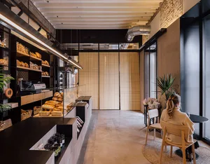 A cozy industrial-style cafe with concrete floors, minimalist decor, and a plant.