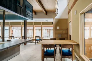 A modern interior featuring a cafe and library space with wooden and concrete elements.