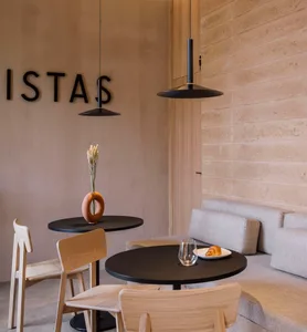 Modern coffee shop interior with wooden furniture, concrete walls, and minimalist design.