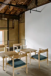 A minimalist modern cafe with wooden furniture and a white wall.