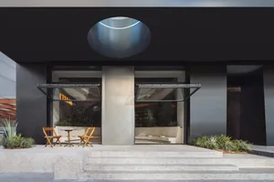 A modern storefront with concrete steps, glass doors, and steel accents.