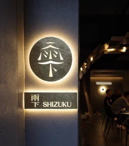 A minimalist restaurant interior with an illuminated metal sign.