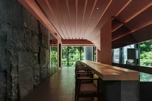 Modern bar area with concrete and wooden elements, featuring a long counter and seating.