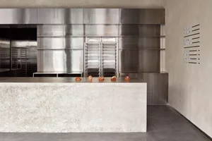 View of a modern cafe interior with a concrete shelf displaying pastries.