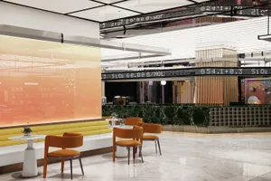 A modern cafe with glass walls, marble floors, and metal seating
