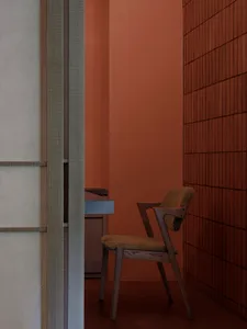 Modern dining room featuring a wooden upholstered chair with a concrete table and a brick wall.