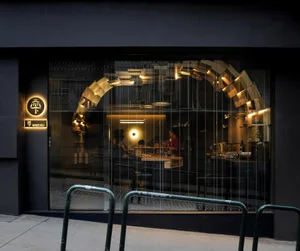 A modern restaurant entrance featuring glass walls and lighting fixtures.
