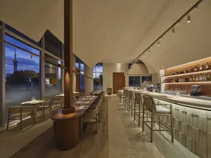 Contemporary restaurant interior with wooden furniture and large windows, featuring modern design elements and accents.