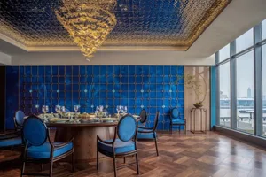 A photograph of a restaurant dining room with a blue tile backdrop, showcasing elegant dining setup and modern design.