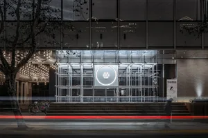 A storefront with a metal and glass modern structure at night.