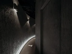 A minimalist interior with black concrete walls and a modern lamp.