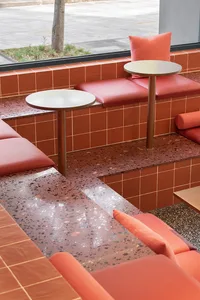 Modern cafe seating with red cushions on a terrazzo floor and table.