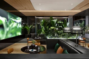 A modern cafe with wooden decor, featuring green plants and a large screen.