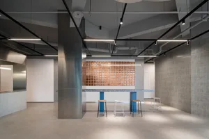 Modern coffee shop interior featuring metal, concrete, and terracotta accents with a sleek, industrial design.