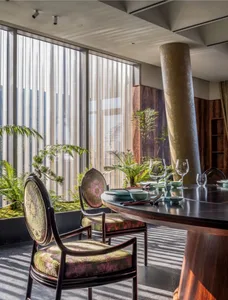 A modern dining room featuring wooden furniture and greenery.