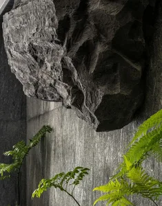 A modern interior design featuring a concrete rockery with green ferns.