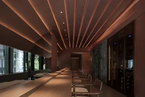 A sleek, modern restaurant bar with wooden seating and stone walls.