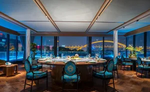 A modern restaurant with glass walls and a view of a bridge at night