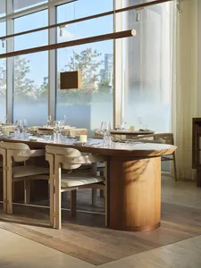 A modern restaurant interior featuring wooden tables and chairs with white plastic seats.