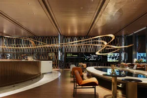 A modern interior design of a sports-themed bar featuring metallic walls and seating areas with orange accents.